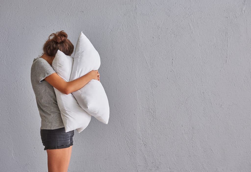 A woman squeezing two pillows.