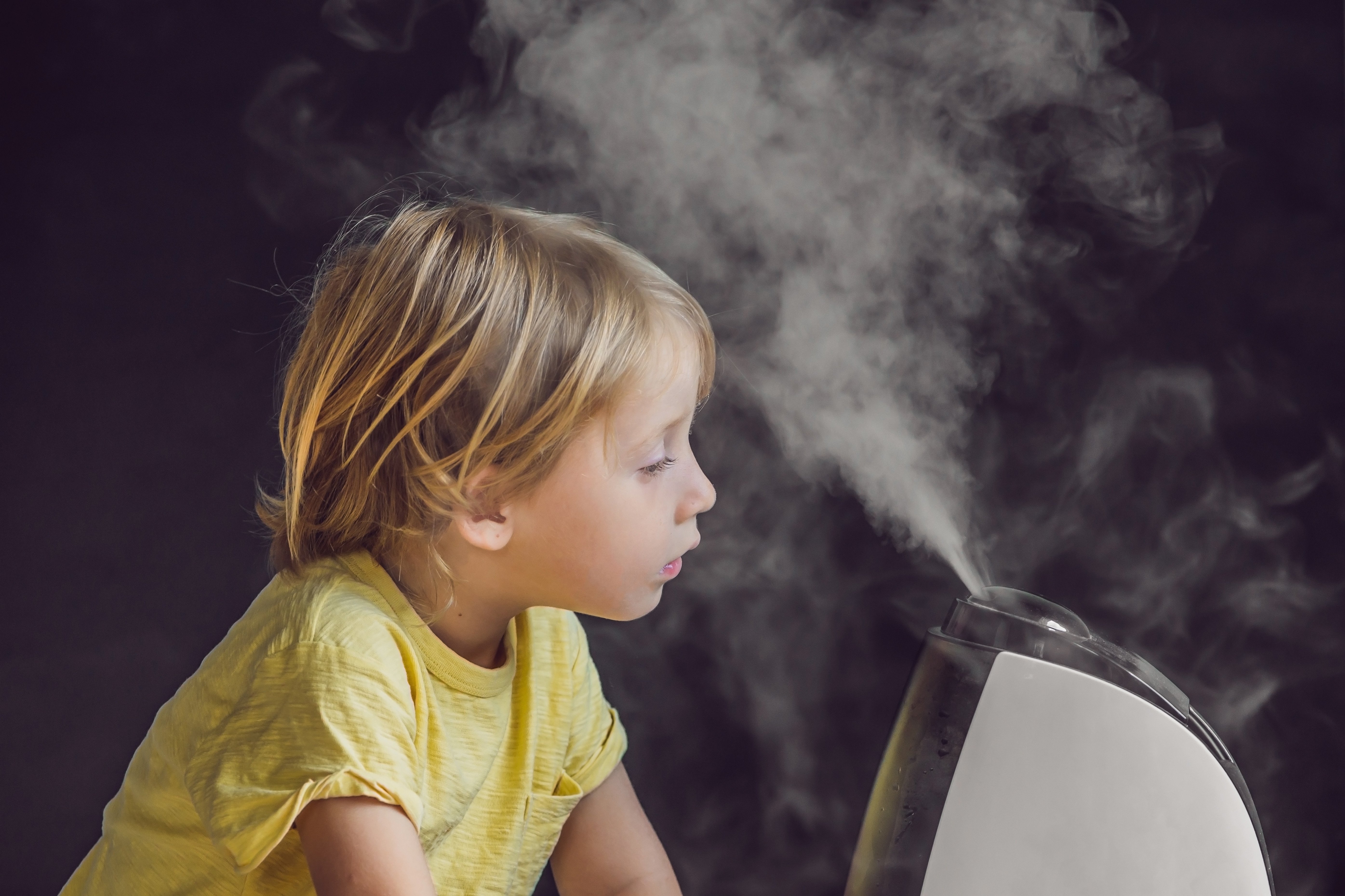 Young girl with face in front of humidifier