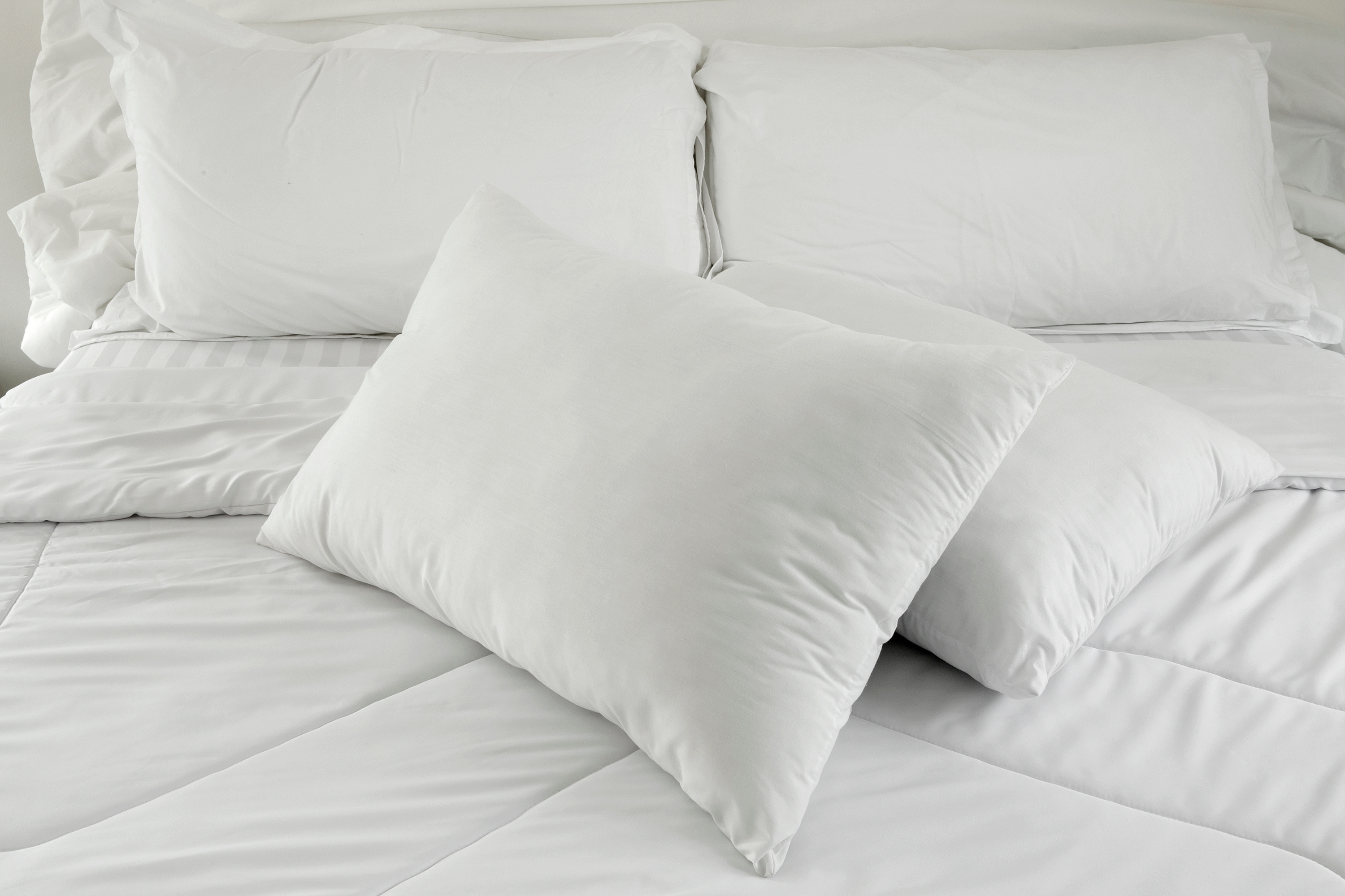 bed with 4 pillows and all white bedding