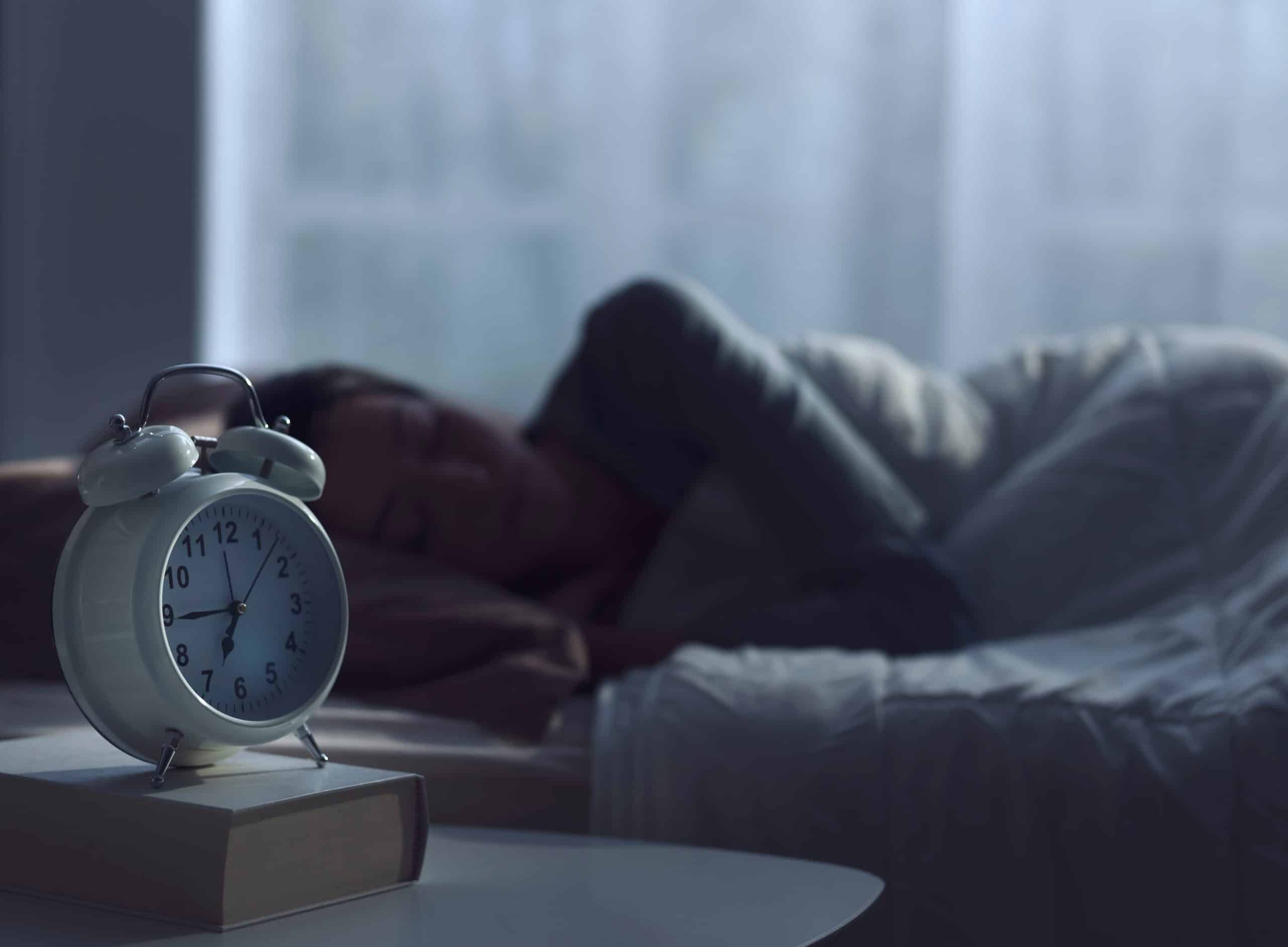 person sleeping in dark room with clock