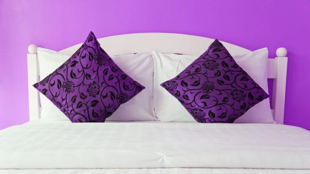 white headboard with purple background and purple pillows