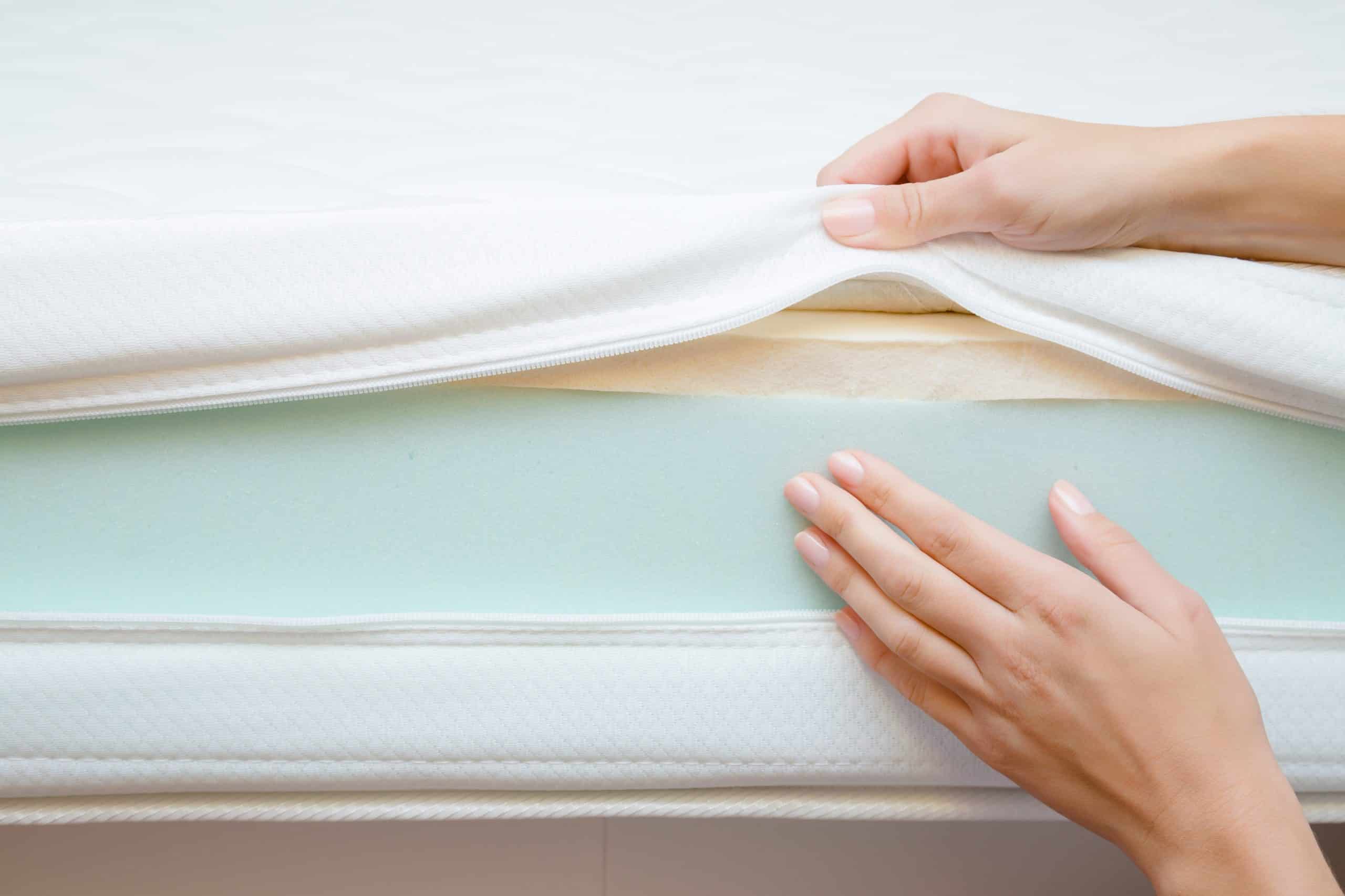 hands lifting up mattress pad to touch foam mattress
