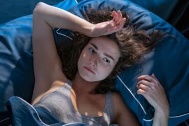 Young woman in bed unable to sleep