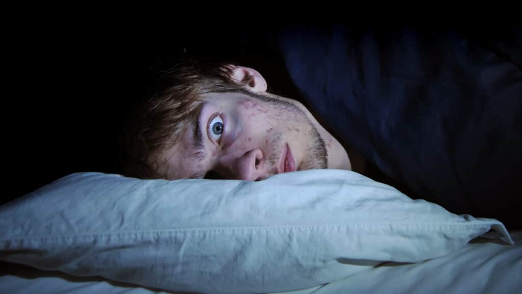 closeup of man in bed looking disturbed