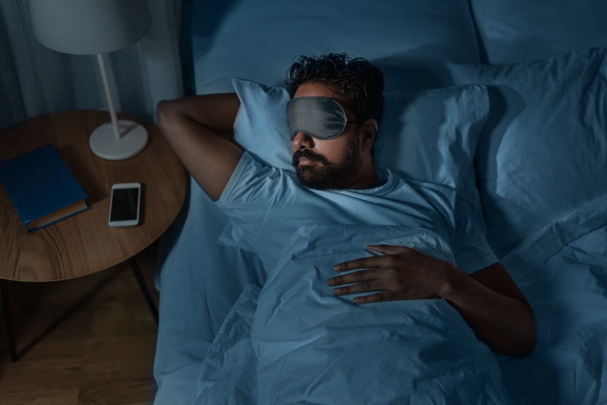 Man sleeps in darkness with eye mask