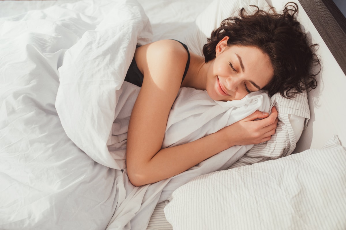 Woman cuddles up with blanket and pillow sleeping